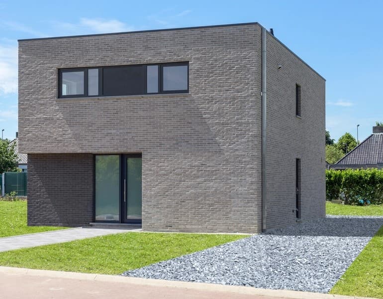 Maison contemporaine en brique grise avec fenêtres bandeau et porte vitrée en aluminium noir