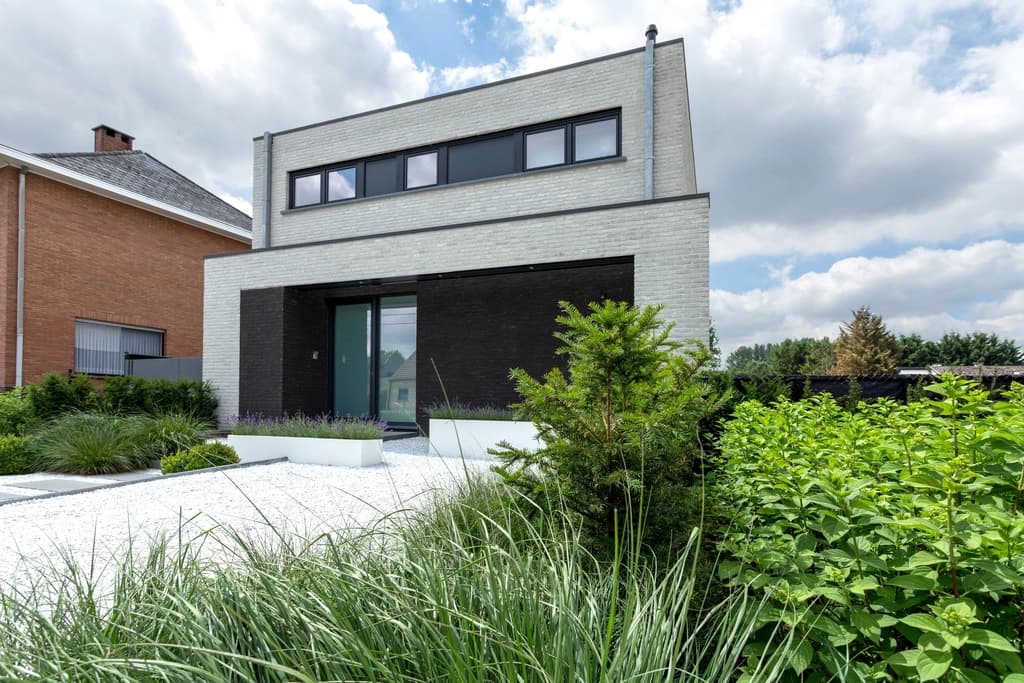Maison contemporaine en brique blanche avec menuiseries aluminium anthracite et porte d'entrée vitrée