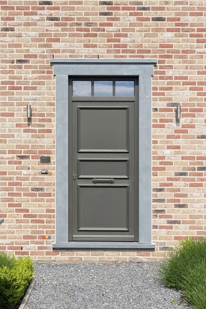 Porte d'entrée aluminium anthracite avec imposte vitrée, encadrement en pierre bleue sur mur de briques